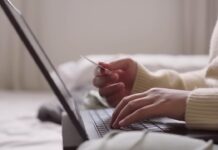 Credit Card Rewards in 2026 – How to Use Points Without Overspending A person holds a credit card while using a laptop at home