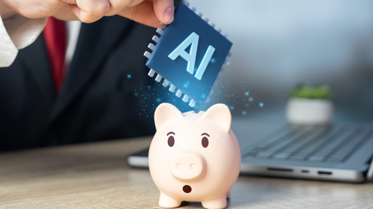 A person drops an AI chip into a piggy bank beside a laptop