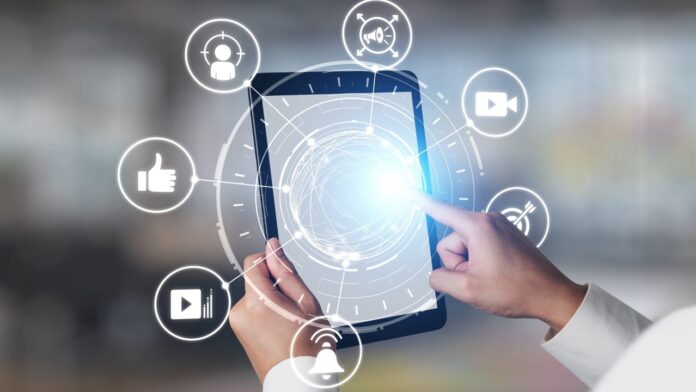 Hand using a tablet with digital media icons around the screen