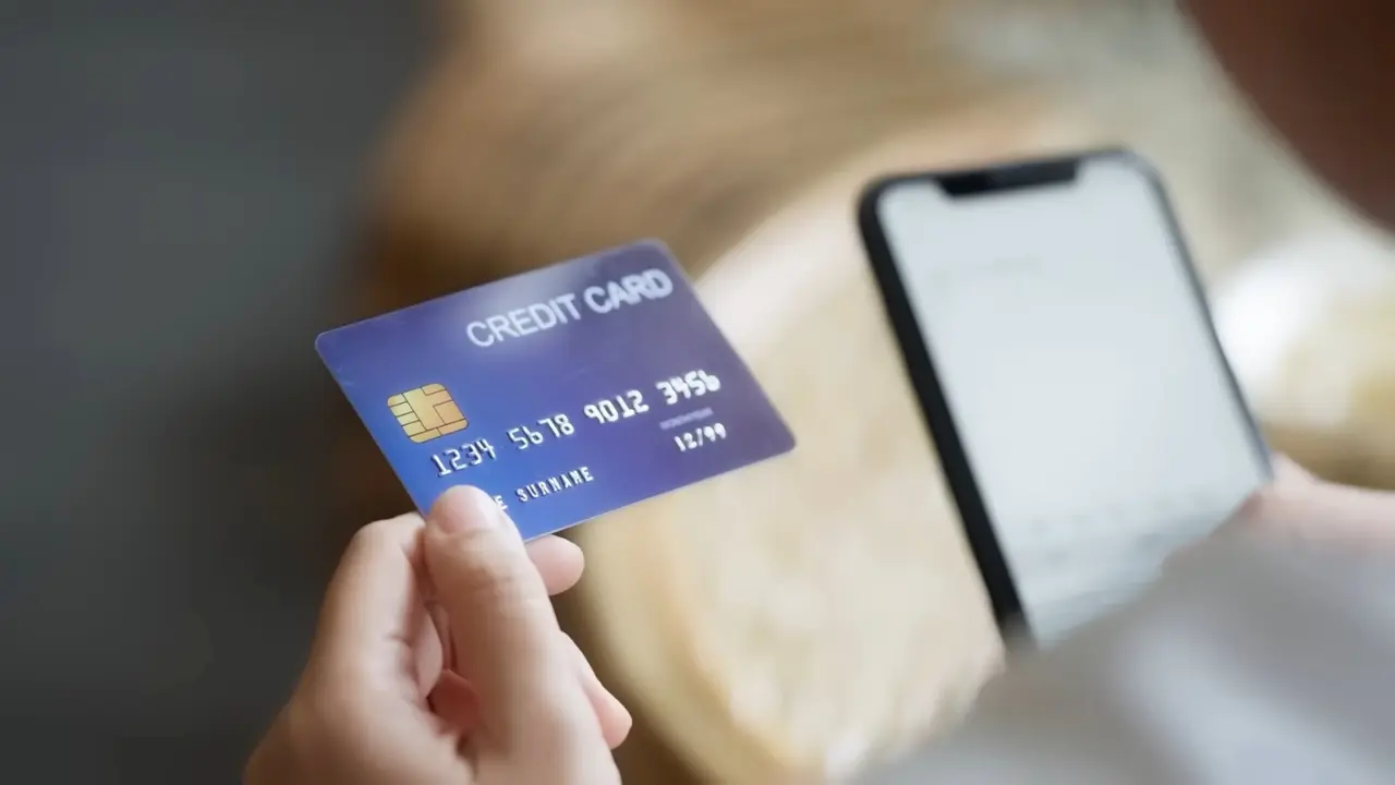 A person holds a credit card near a smartphone screen