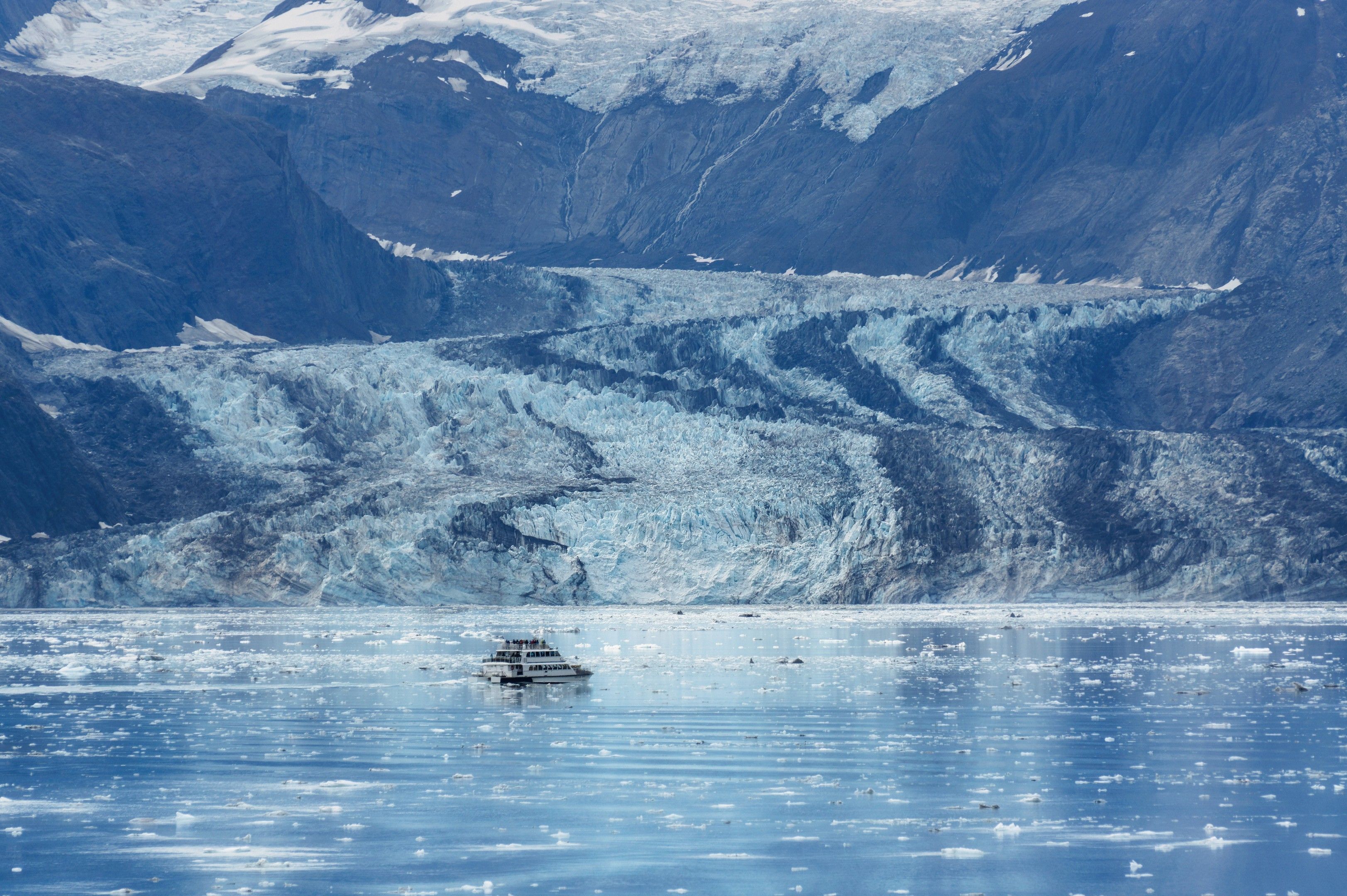 Alaskan glacier and ship navigating icy waters from an aerial perspective