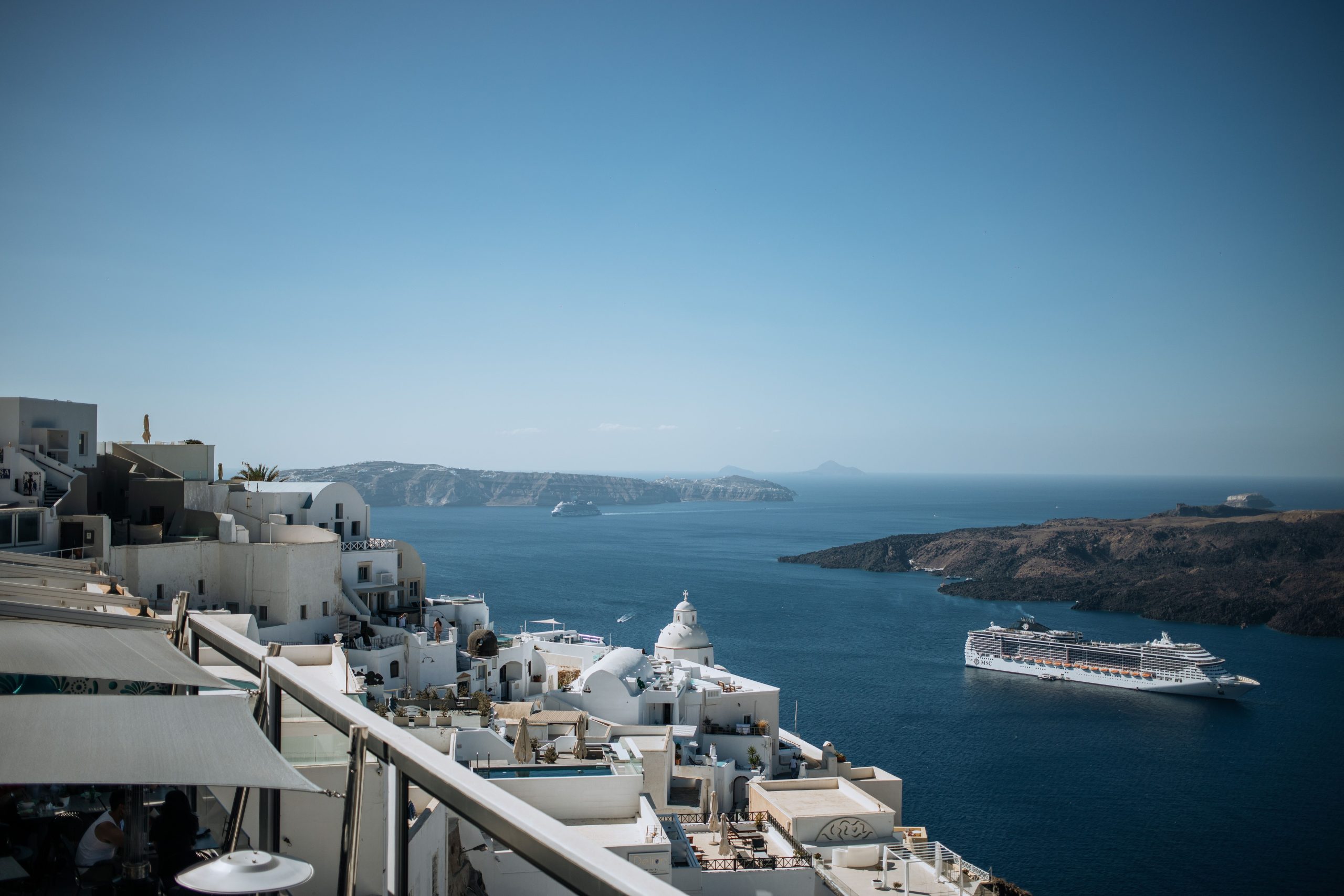 santorini-cruise-destination-aegean Santorini's whitewashed buildings overlooking the Aegean Sea with a cruise ship offshore