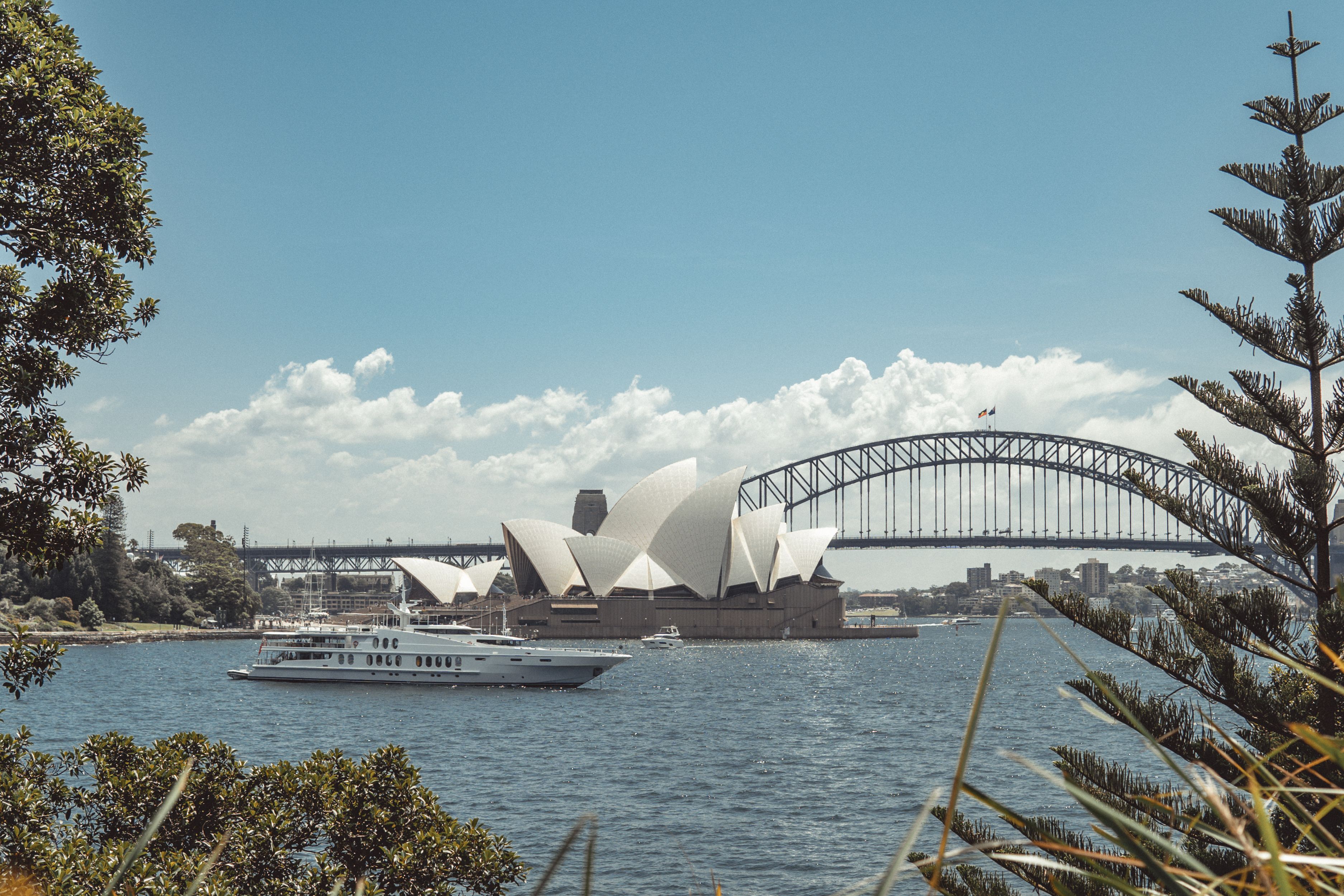 Sydney Opera House and Harbour Bridge viewed from the water with a yacht in front